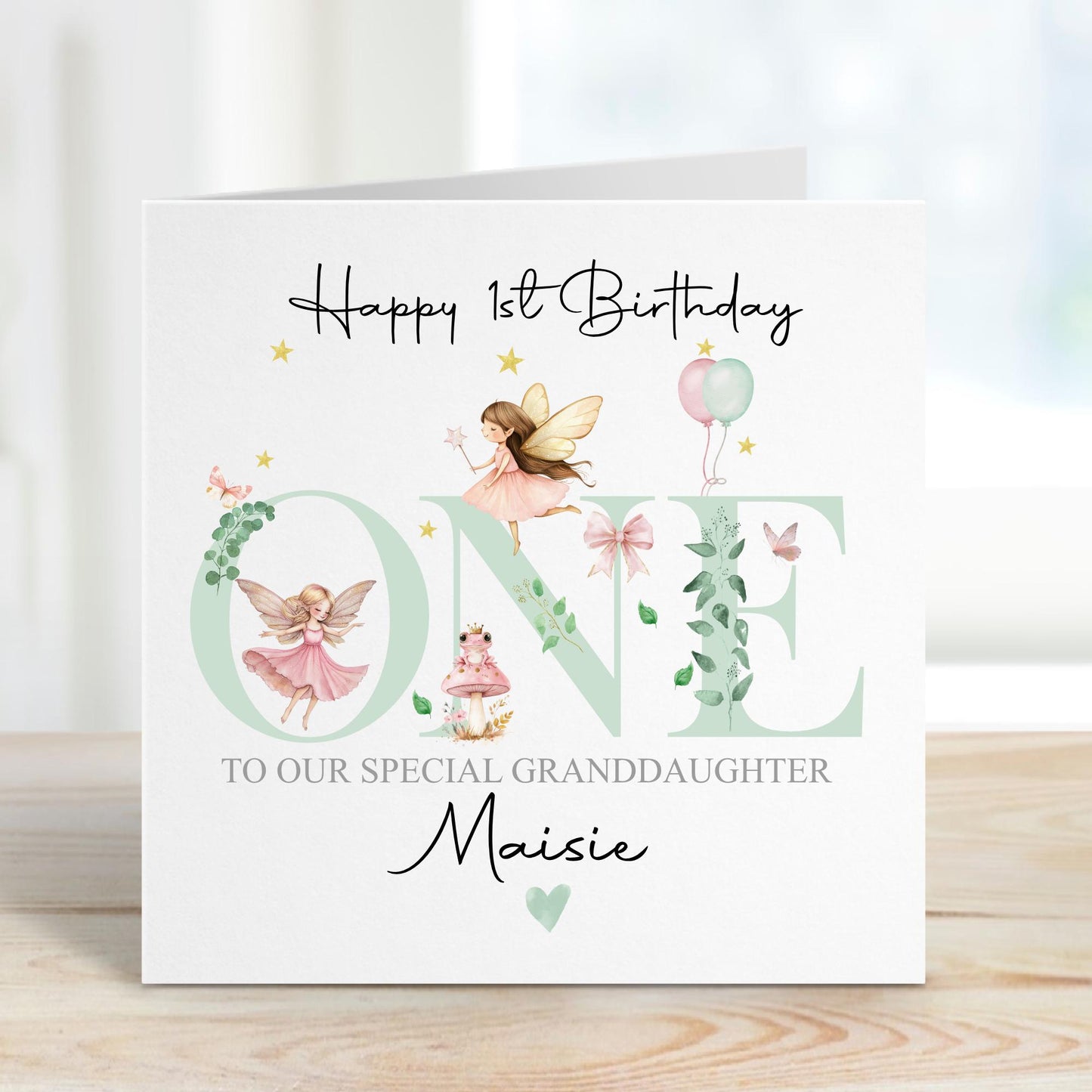 White linen luxury fairy 1st birthday card featuring beautiful little fairies & a pink toadstool & frog prince & the number one in pale green & the wording Happy 1st birthday to our special daughter, granddaughter, niece, special little girl, can be adapted to any relation. Personalised with childs name.
