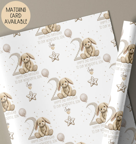 Personalised second birthday gift wrap featuring a repeating pattern of a cute neutral-toned bunny, balloons, and a large number 2. Design includes the wording ‘Happy 2nd Birthday to our Wonderful Son’ and is personalised with a name. Soft beige and white colour palette with polka dot details.