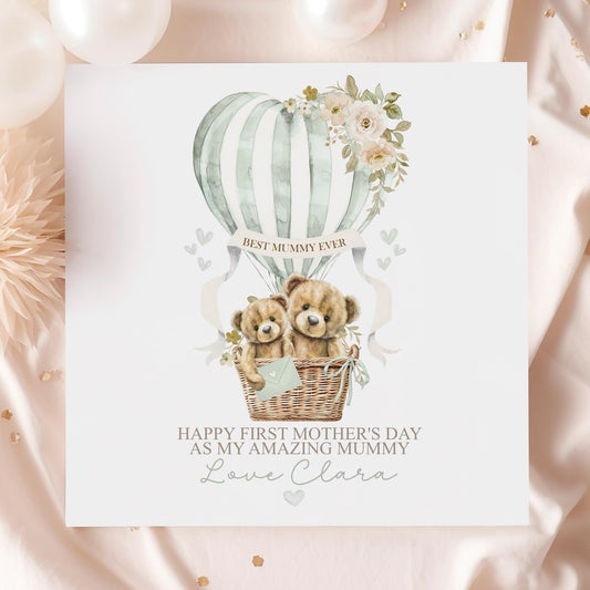 Personalised first Mother’s Day card for new mum, featuring two teddy bears in a wicker basket inside a sage green hot air balloon with soft florals and hearts and the wording 'Happy 1st mothers day as my amazing mummy' Personalised with a name.