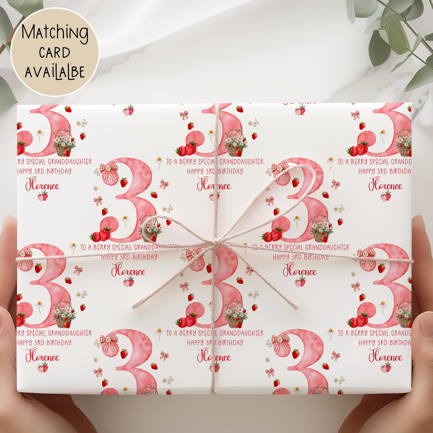 Personalised gift wrap for a 3rd birthday featuring a large red watercolor number &#39;3&#39; adorned with strawberries, gingham bows, and flowers. The design includes the text &#39;To a berry special granddaughterDaughter/any relation Happy 3rd Birthday&#39; Personalised with a name.