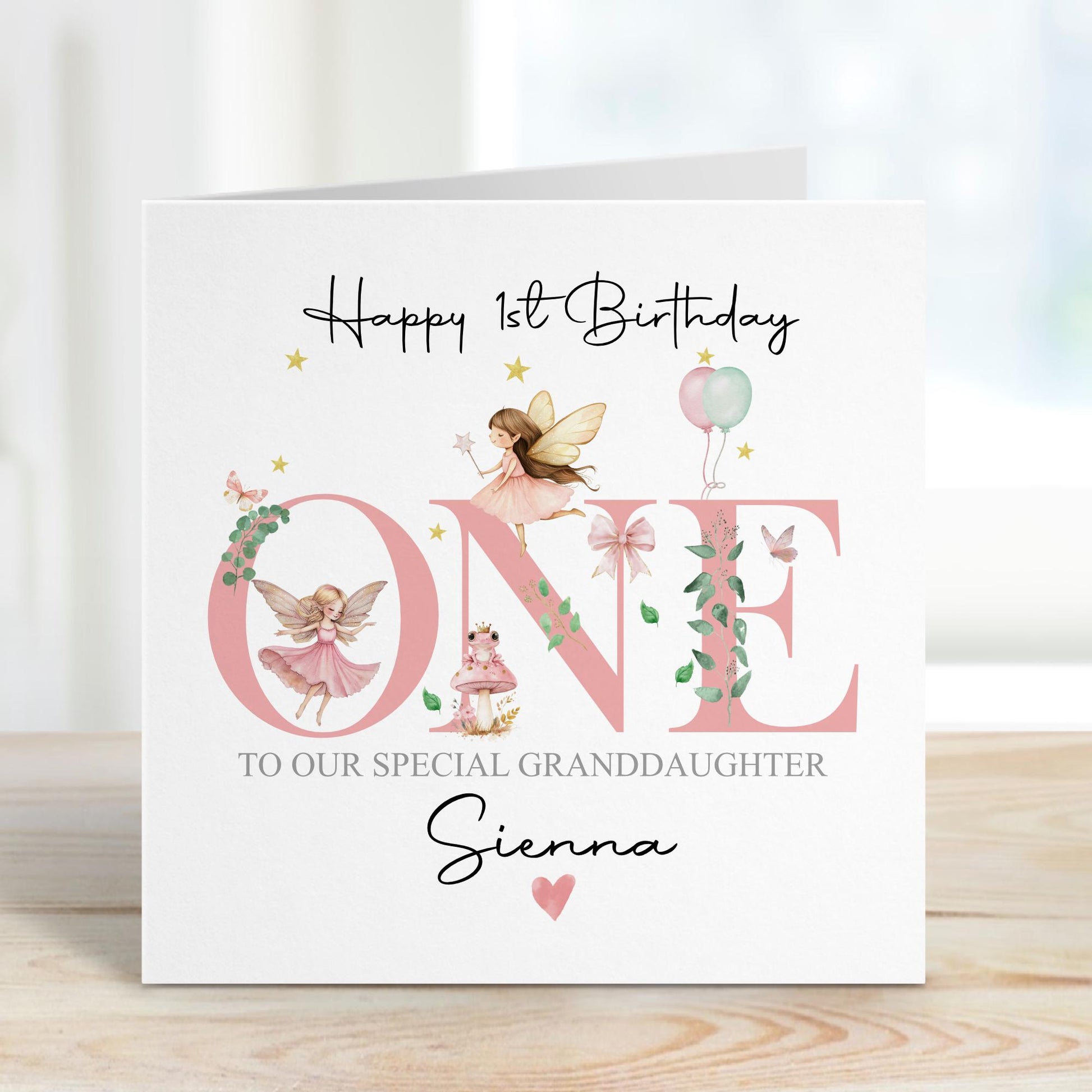 White linen luxury fairy 1st birthday card featuring beautiful little fairies & a pink toadstool & frog prince & the number one in pink & the wording Happy 1st birthday to our special daughter, granddaughter, niece, special little girl, can be adapted to any relation. Personalised with childs name.