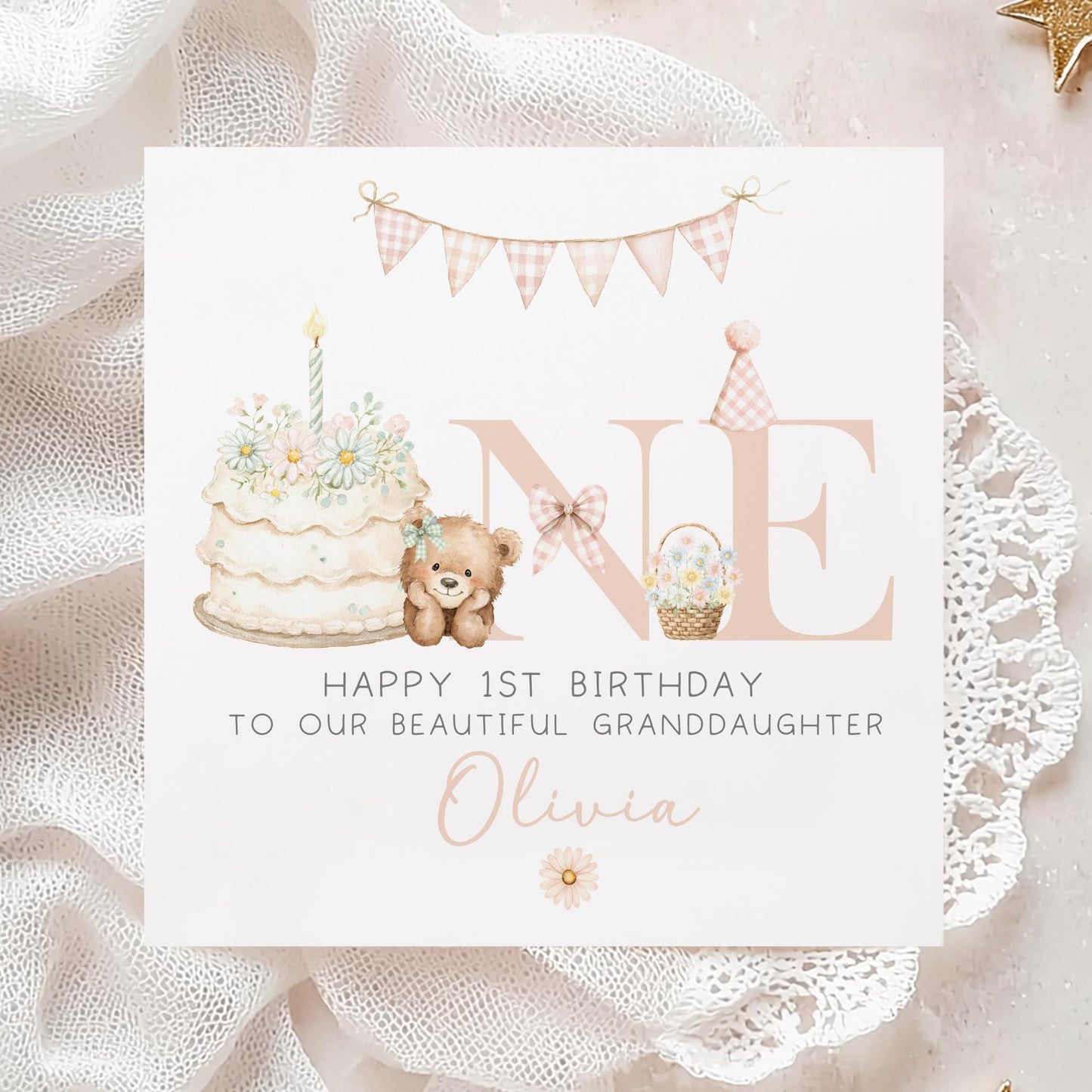 Square personalised first birthday greeting card featuring soft pastel illustrations including a teddy bear, birthday cake with candle, bunting, flowers and a gift basket. The design displays the word ‘ONE’ with decorative details and space for personalised name and relation text.