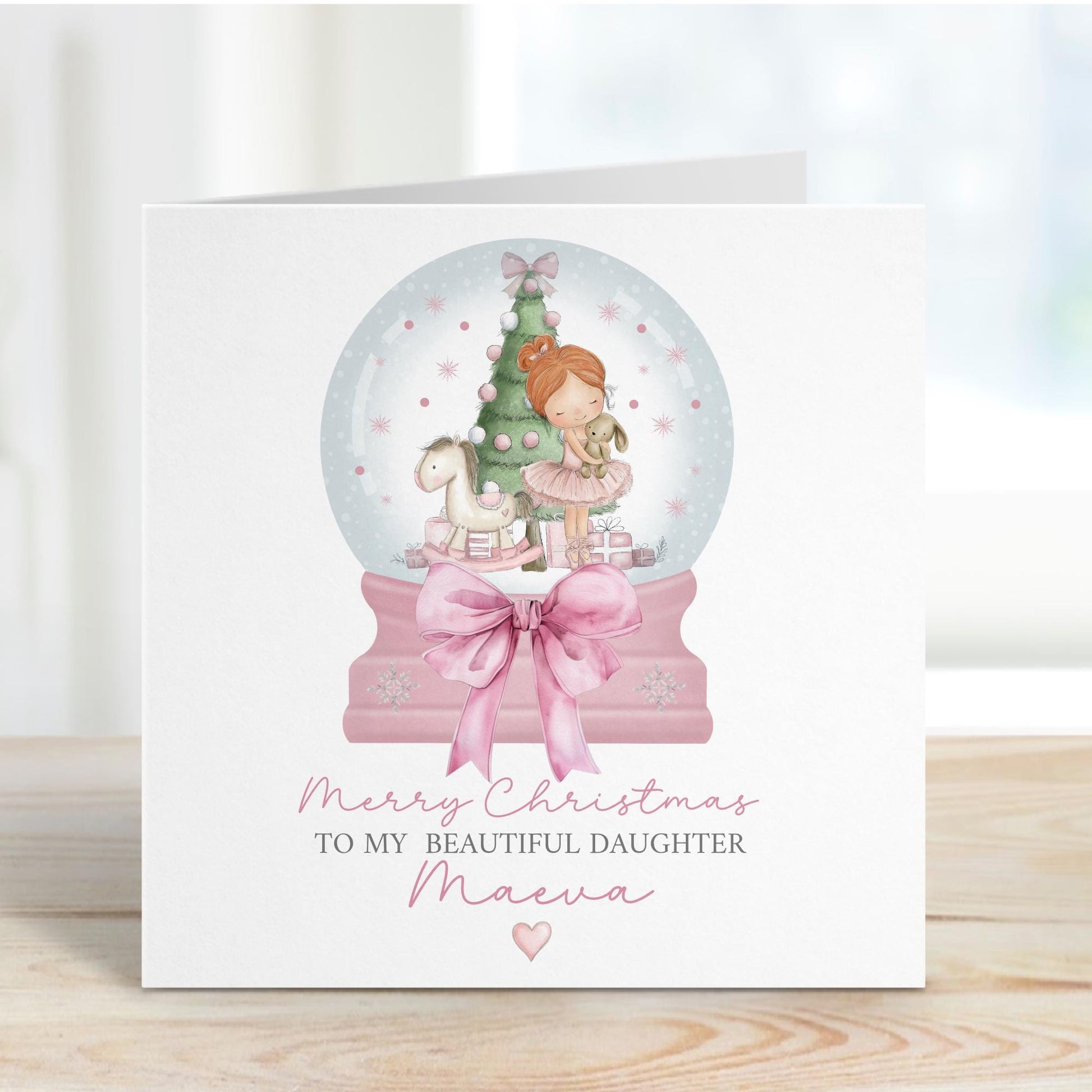 Square personalised Christmas card featuring a ballerina holding a teddy inside a pink snow globe with a Christmas tree, rocking horse, and presents. Text reads “Merry Christmas to our beautiful granddaughter/Daughter/Any relations&quot; Personalised with a name.