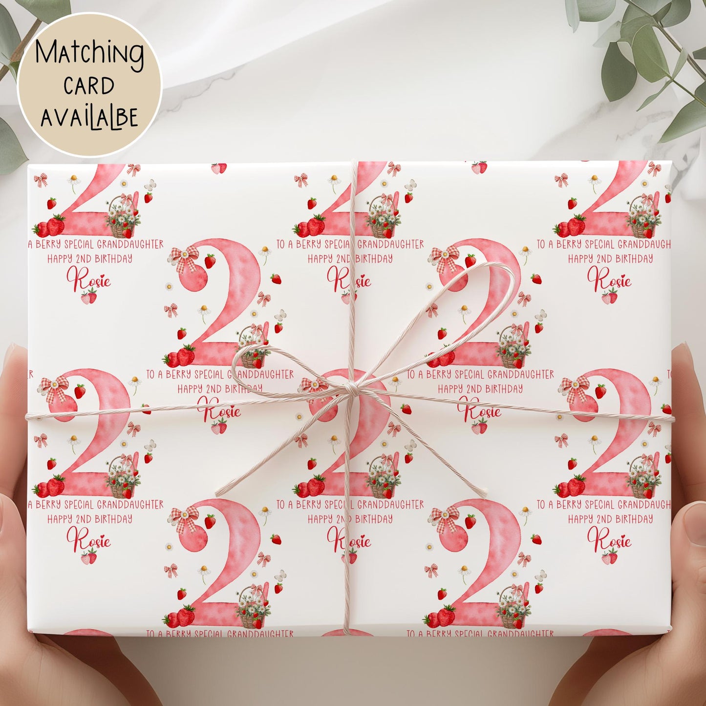Personalised gift wrap for a 2nd birthday featuring a large red watercolor number &#39;2&#39; adorned with strawberries, gingham bows, and flowers. The design includes the text &#39;To a berry special granddaughterDaughter/any relation Happy 1st Birthday&#39; Personalised with a name.