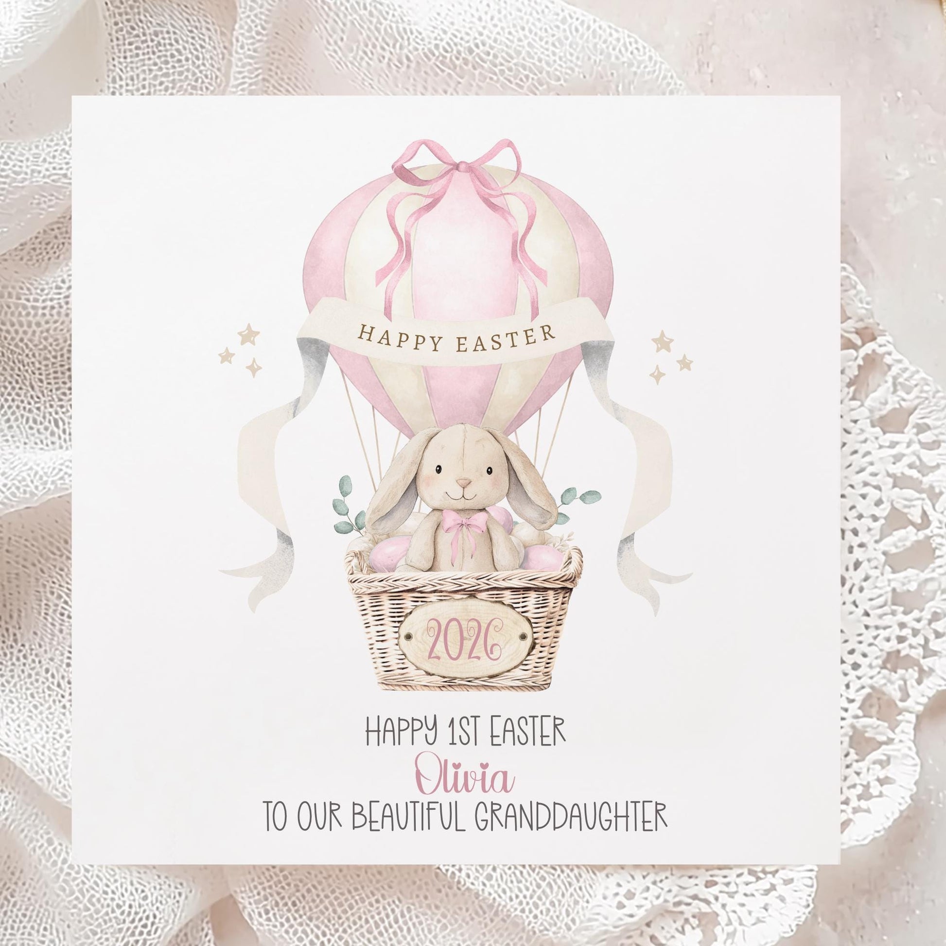 Square personalised Easter greeting card featuring an illustrated bunny sitting in a wicker basket hot air balloon in soft pink pastel tones. The design includes Easter eggs, ribbon details and a banner reading ‘Happy Easter’. The card has space for personalised text for name, year and relation.