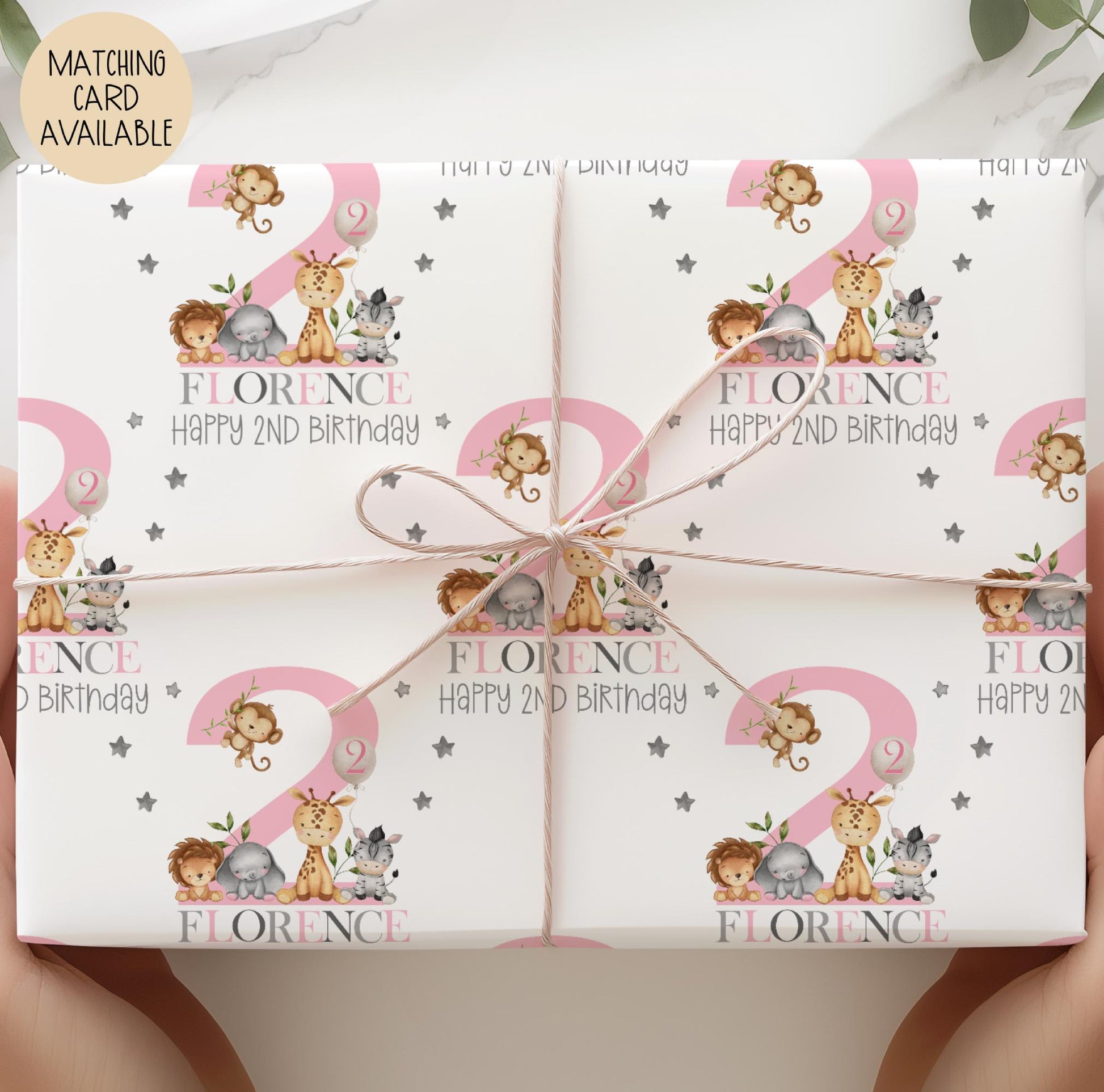 Personalised gift wrap for a 2nd birthday featuring a large pink number &#39;2&#39; surrounded by cute safari animals & grey stars. The design includes the text &#39; Happy 2nd Birthday&#39; Personalised with a name in multi-coloured text.