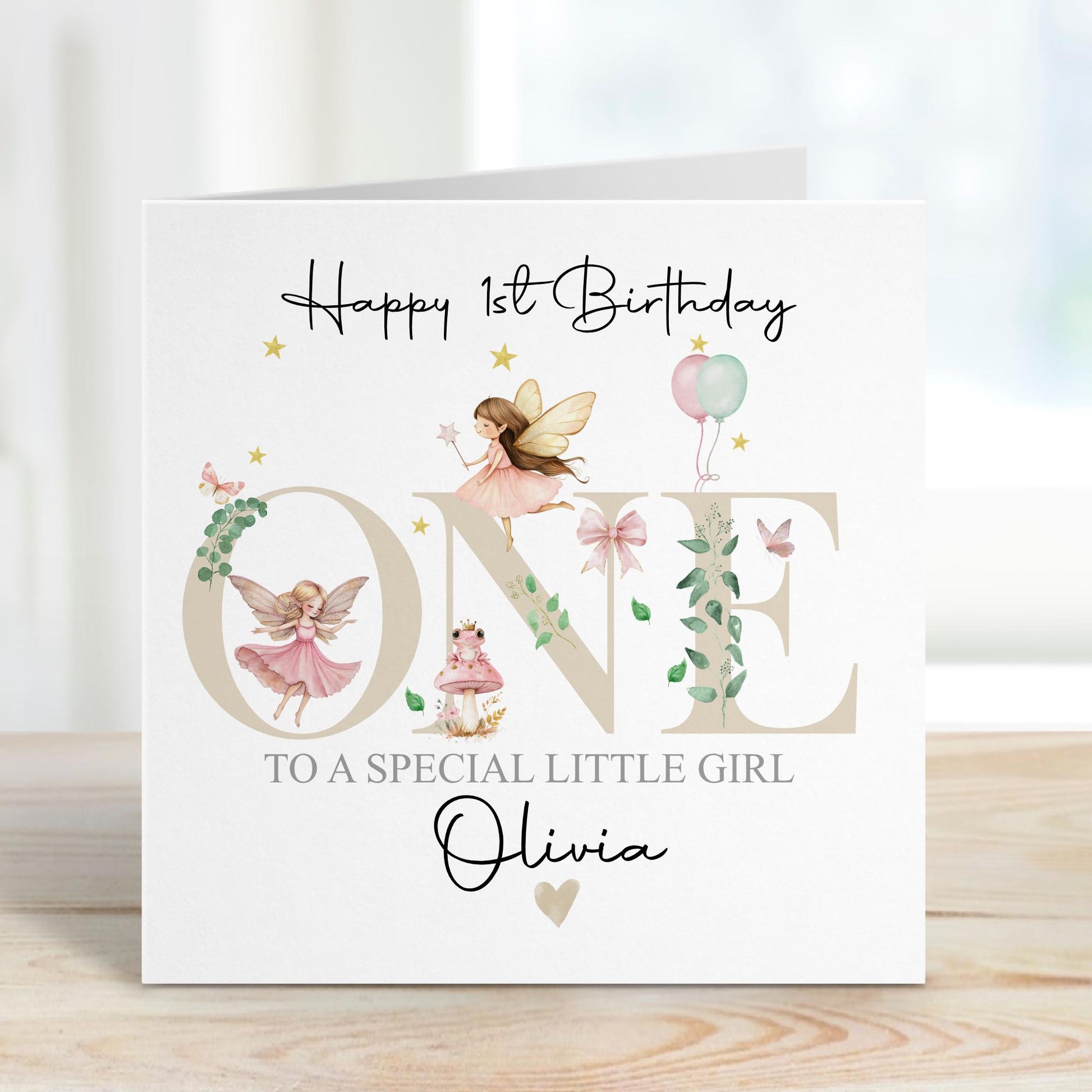 White linen luxury fairy 1st birthday card featuring beautiful little fairies & a pink toadstool & frog prince & the number one in neutral beige & the wording Happy 1st birthday to our special daughter, granddaughter, niece, special little girl, can be adapted to any relation. Personalised with childs name.