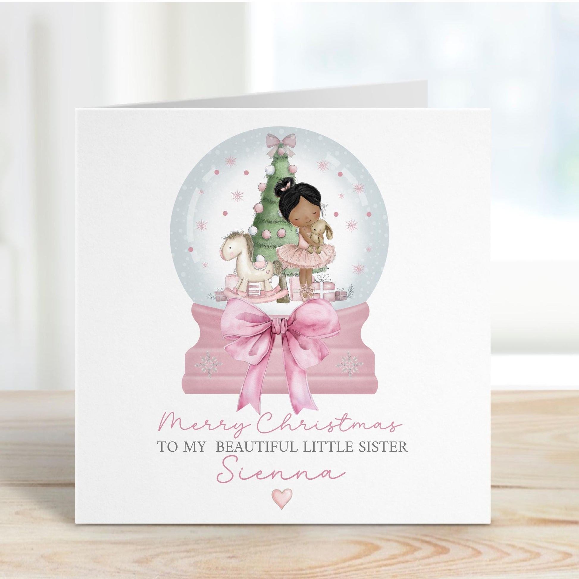 Square personalised Christmas card featuring a ballerina holding a teddy inside a pink snow globe with a Christmas tree, rocking horse, and presents. Text reads “Merry Christmas to our beautiful granddaughter/Daughter/Any relations&quot; Personalised with a name.