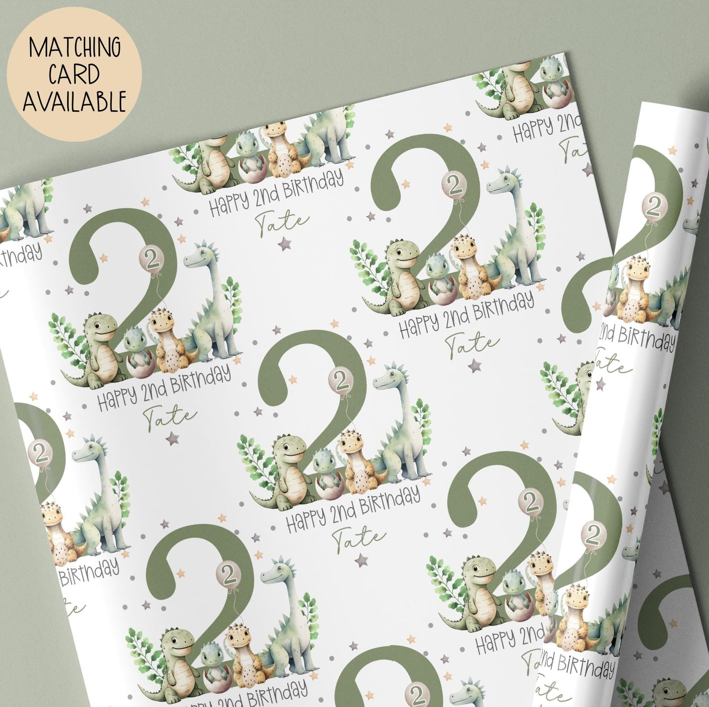 Personalised gift wrap for a 2nd birthday featuring a large sage green number '2' surrounded by cute dinosaurs & stars. The design includes the text ' Happy 2nd Birthday' Personalised with a name.