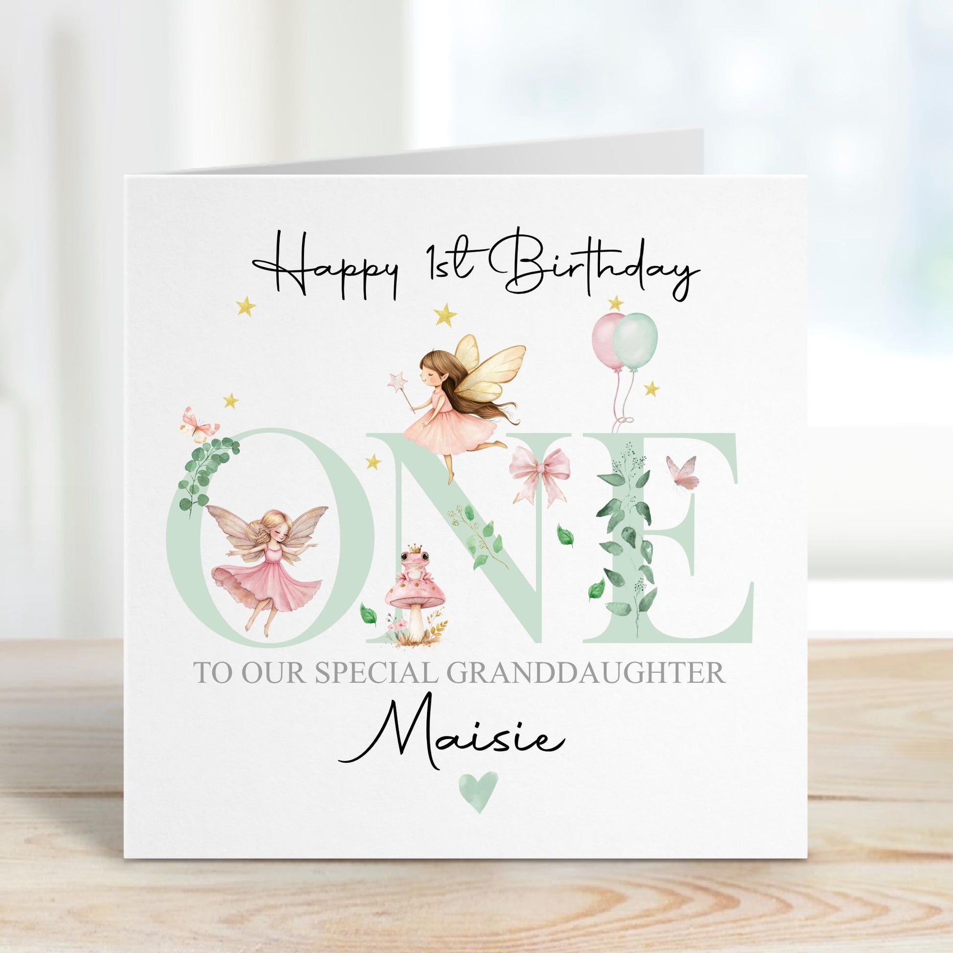 White linen luxury fairy 1st birthday card featuring beautiful little fairies & a pink toadstool & frog prince & the number one in pale green & the wording Happy 1st birthday to our special daughter, granddaughter, niece, special little girl, can be adapted to any relation. Personalised with childs name.
