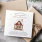 Personalised Christmas card featuring a cosy red snow-covered house with a wreath on the door and wrapped gifts outside. Surrounded by golden stars, the card reads “Happy First Christmas in Your New Home” and includes a short festive poem. The design can be customised with names and the year.