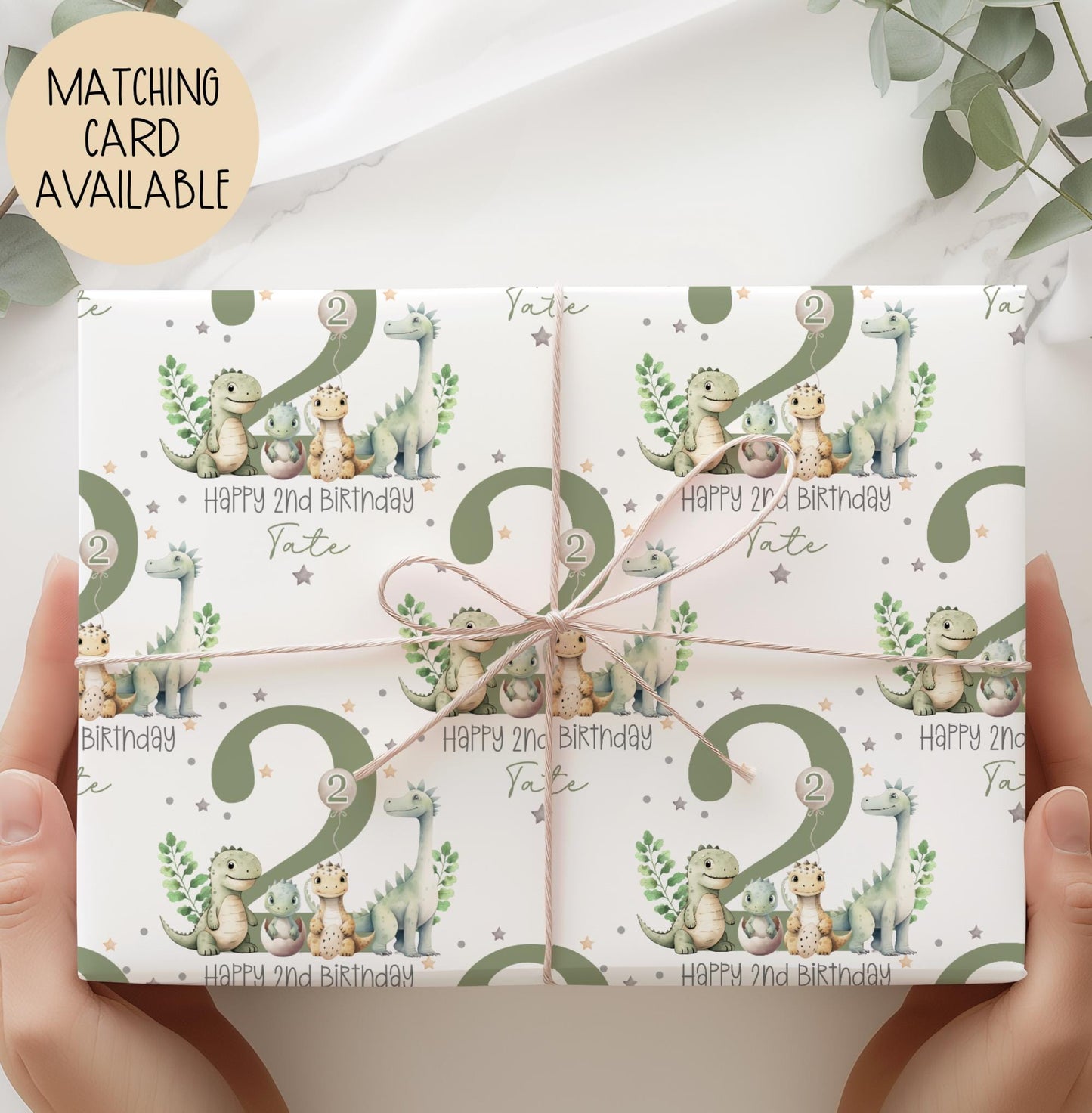 Personalised gift wrap for a 2nd birthday featuring a large sage green number '2' surrounded by cute dinosaurs & stars. The design includes the text ' Happy 2nd Birthday' Personalised with a name.