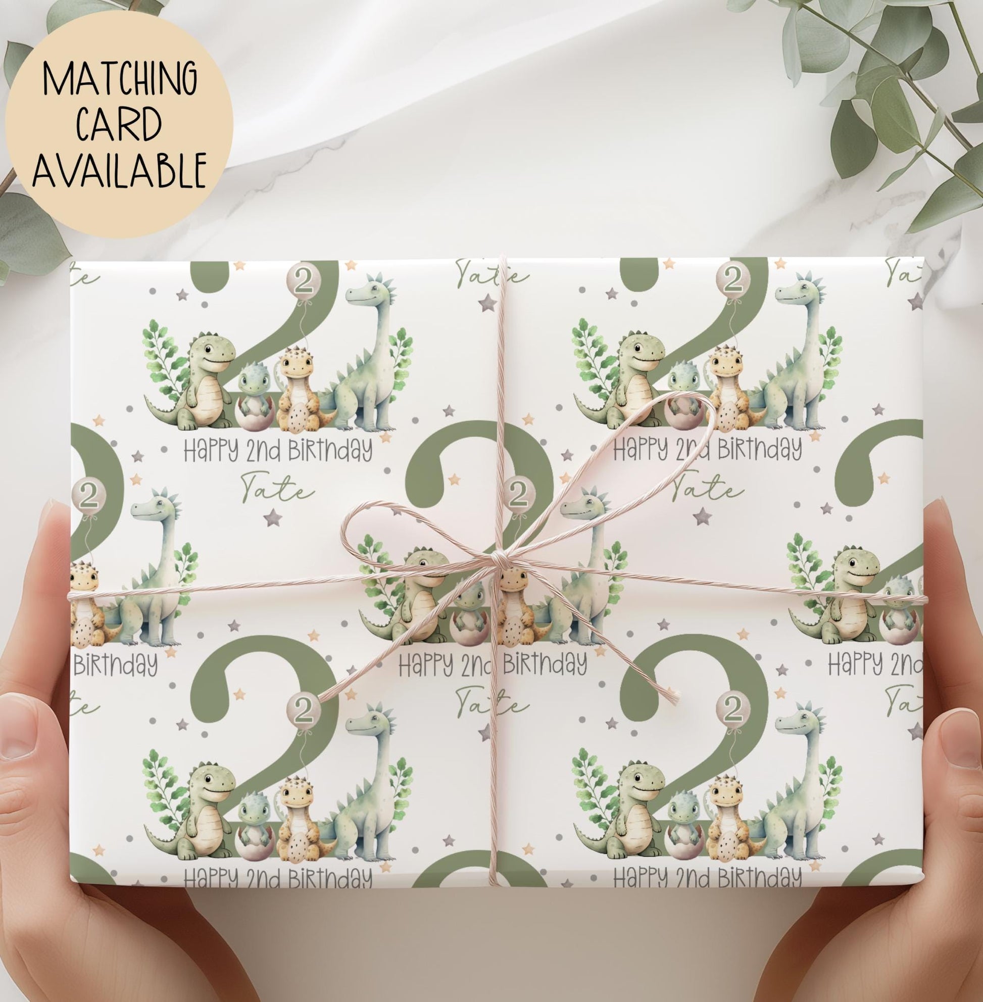 Personalised gift wrap for a 2nd birthday featuring a large sage green number '2' surrounded by cute dinosaurs & stars. The design includes the text ' Happy 2nd Birthday' Personalised with a name.