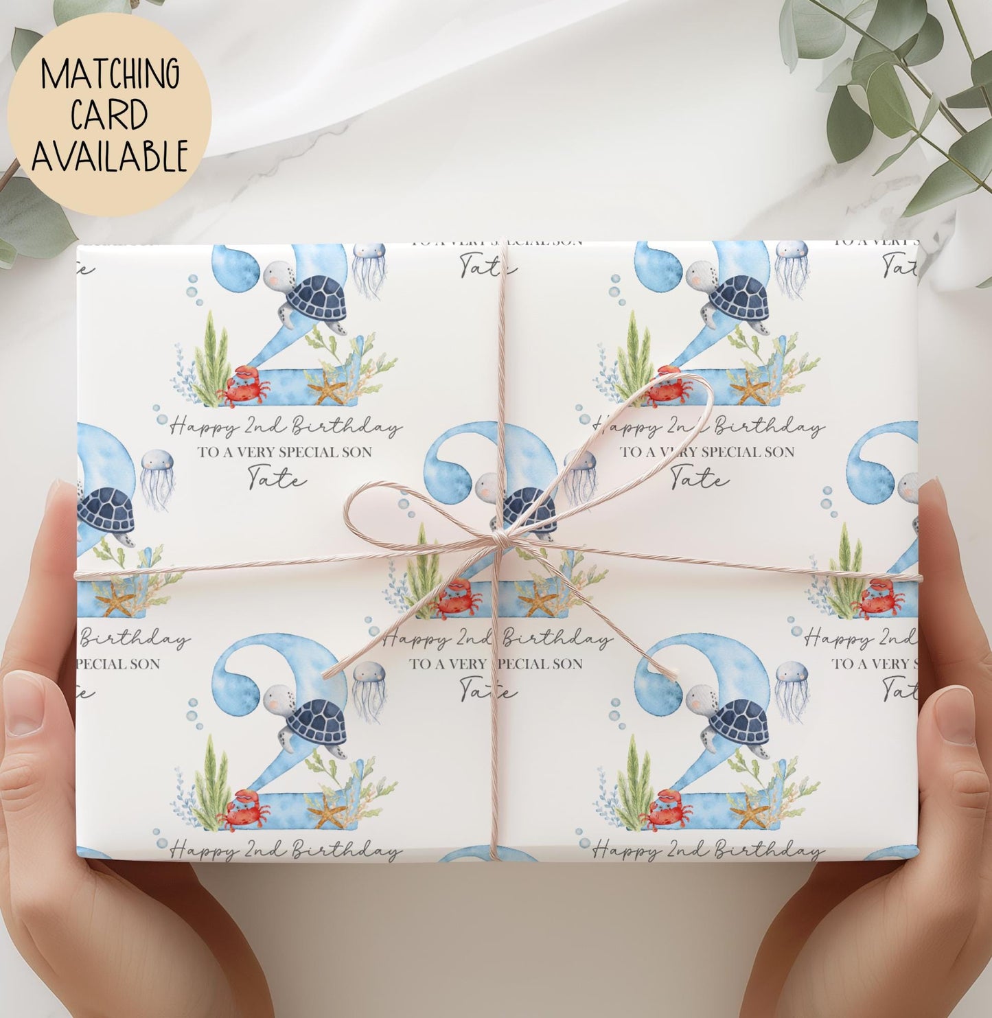 Personalised birthday gift wrap featuring a repeating watercolour design with a large blue number 2, turtle, crab, jellyfish and sea plants, with “Happy 2nd Birthday” text and space for a personalised name.
