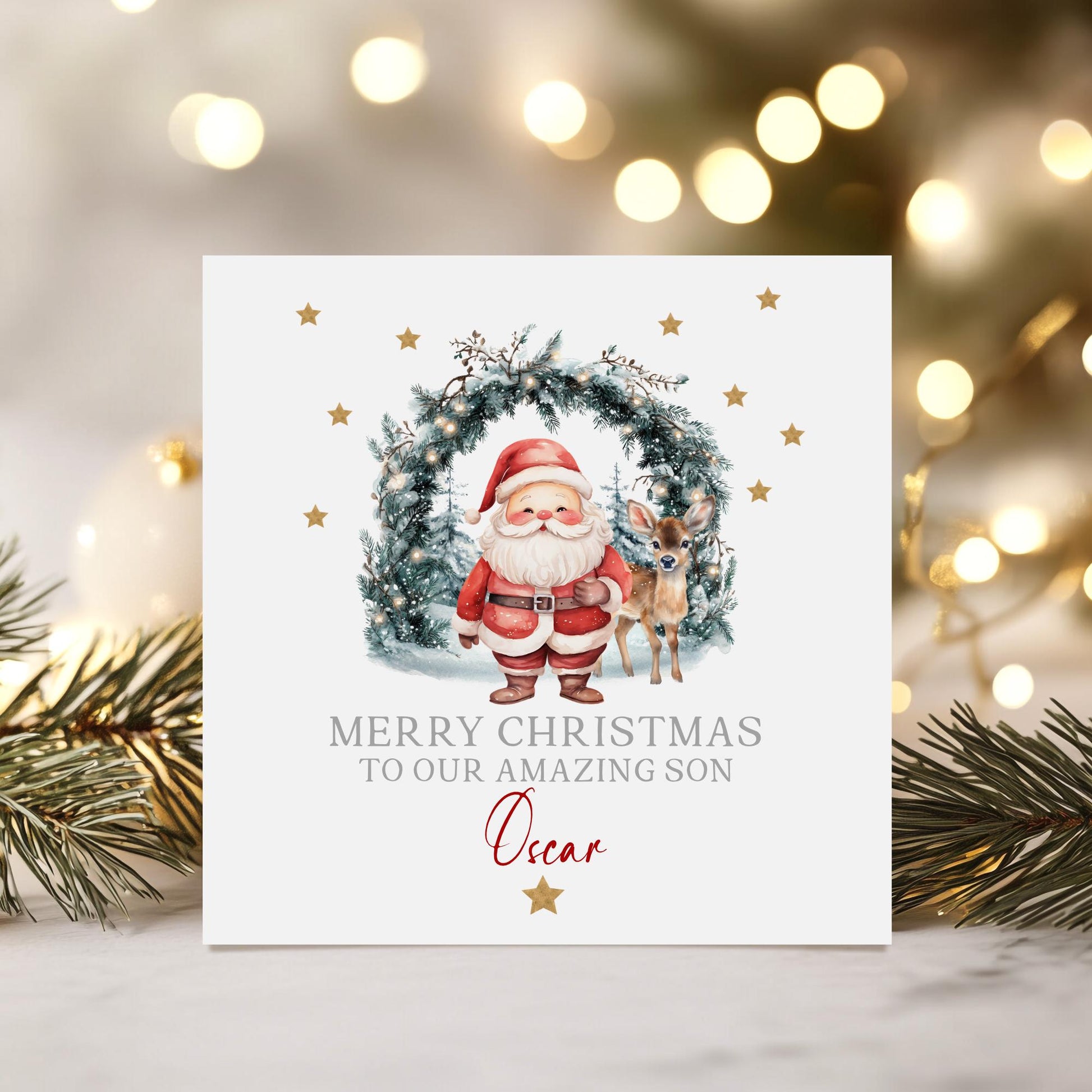 Personalised Christmas card featuring Santa and a reindeer standing in front of a festive wreath with twinkling lights, gold stars, and the message ‘Merry Christmas to our amazing granddaughter Hollie’ printed on the front. High-quality 300gsm card.