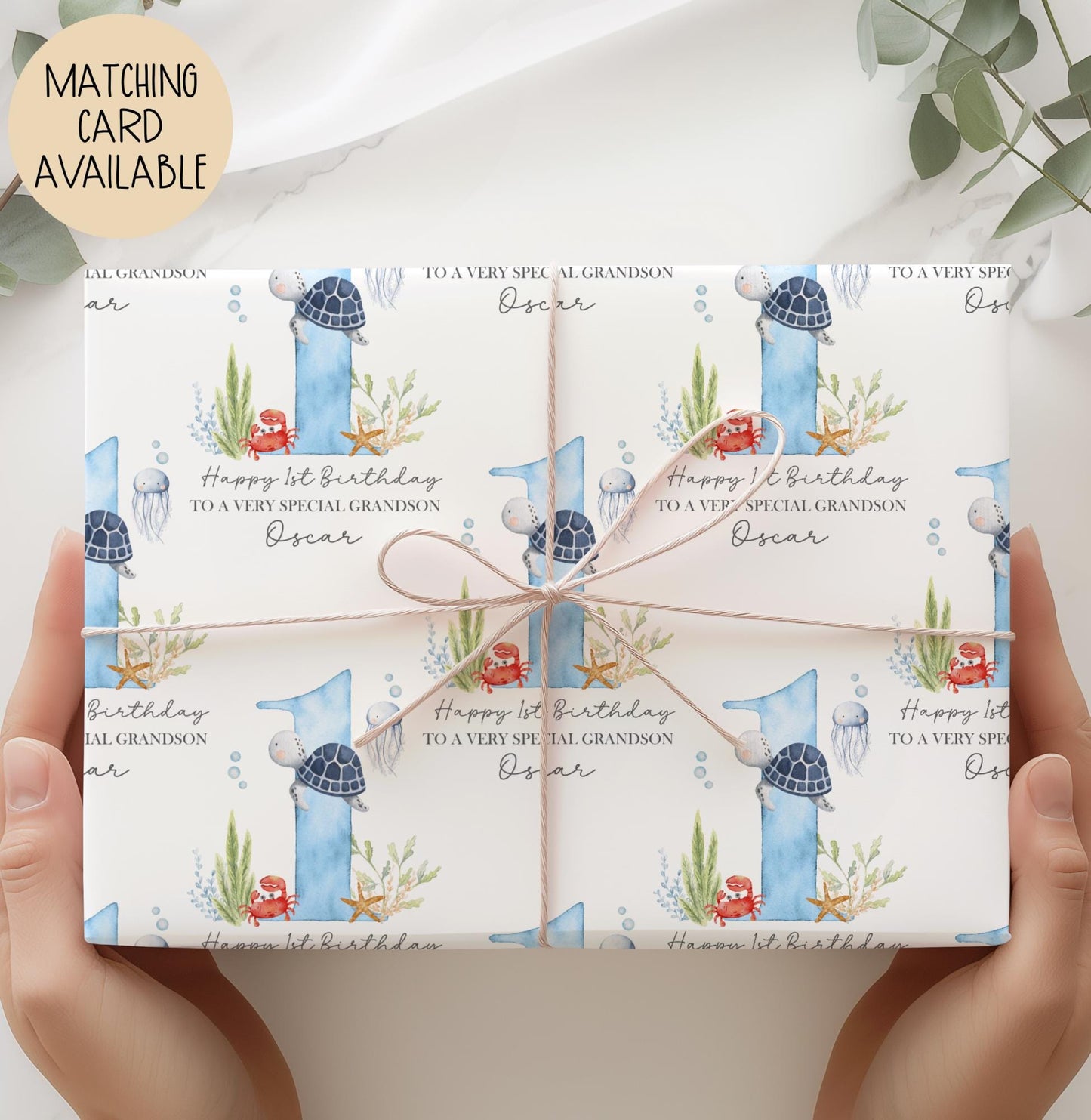 Personalised birthday gift wrap featuring a repeating watercolour design with a large blue number one, turtle, crab, jellyfish and sea plants, with “Happy 1st Birthday” text and space for a personalised name.
