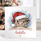 Personalised Christmas card featuring a cute Highland cow wearing a Santa hat with a “Merry Christmas” banner and space for a name. A festive design perfect for all ages.